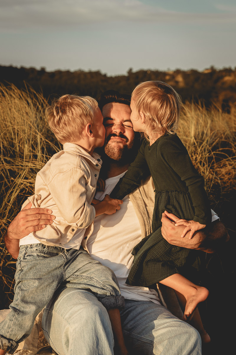 kids kiss their dad on the cheeks