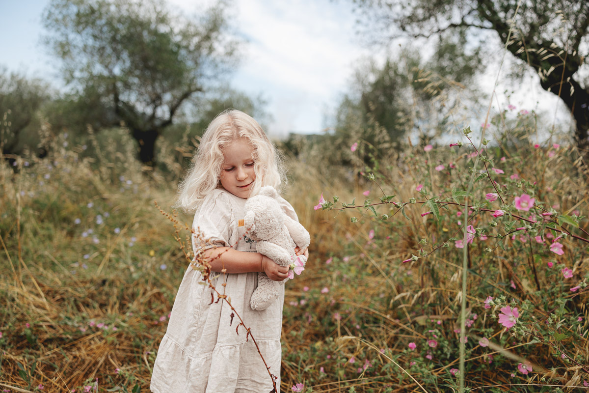 Girl with her teddy bear in an olive orchard