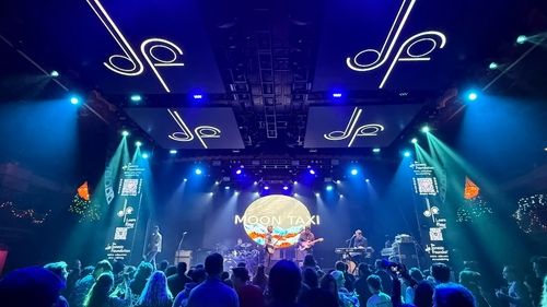 A concert from the audience view with a person making a heart with their hands