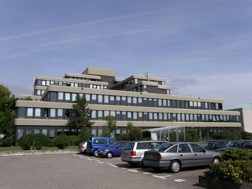 Klinikgebäude der BGL vor der energetischen Sanierung mit mehrstöckiger Fassade und umliegenden Parkplätzen.
