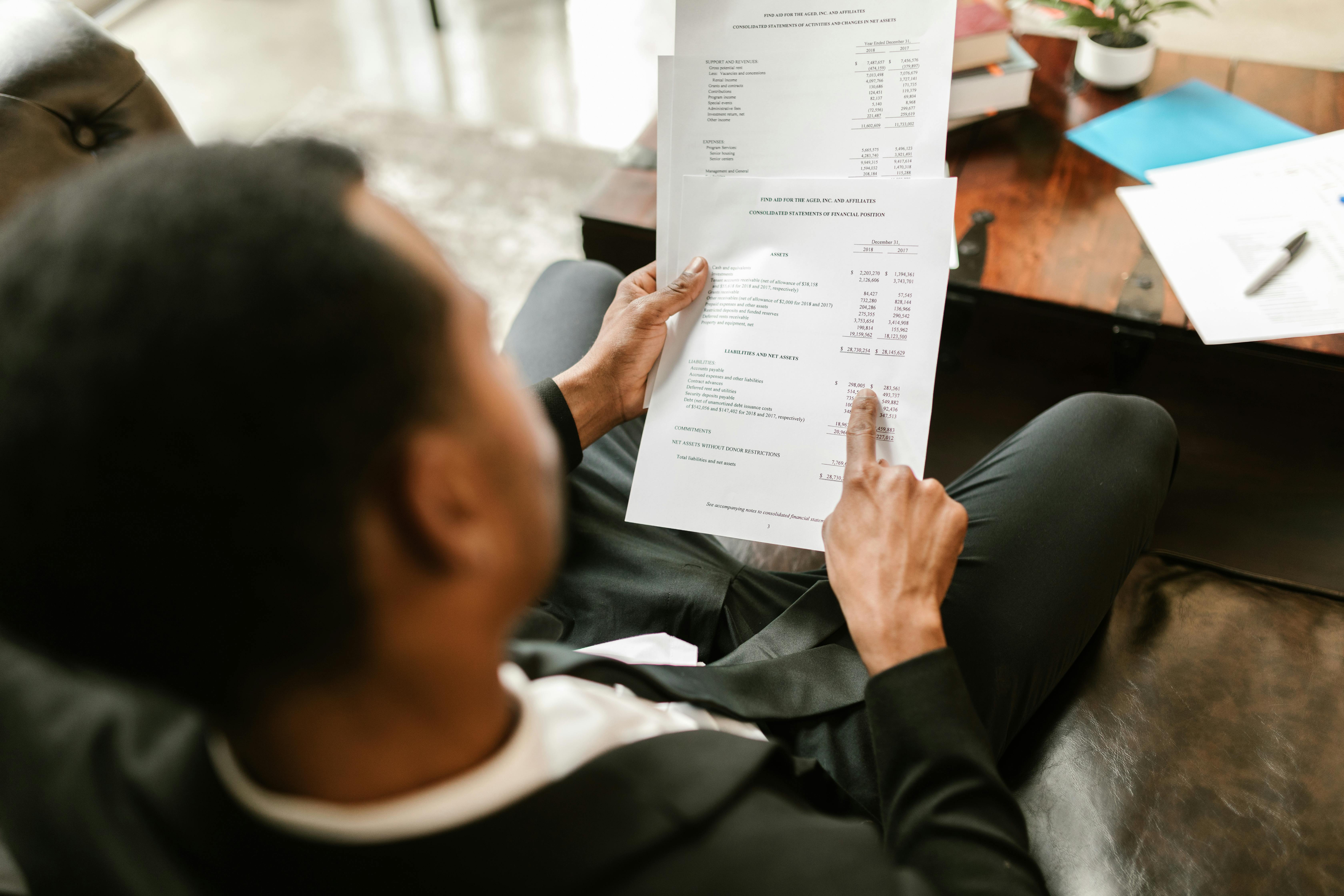 A person in a suit sits on a couch, reviewing financial documents, pointing to steps for filing final tax returns and guidance for executors and spouses.