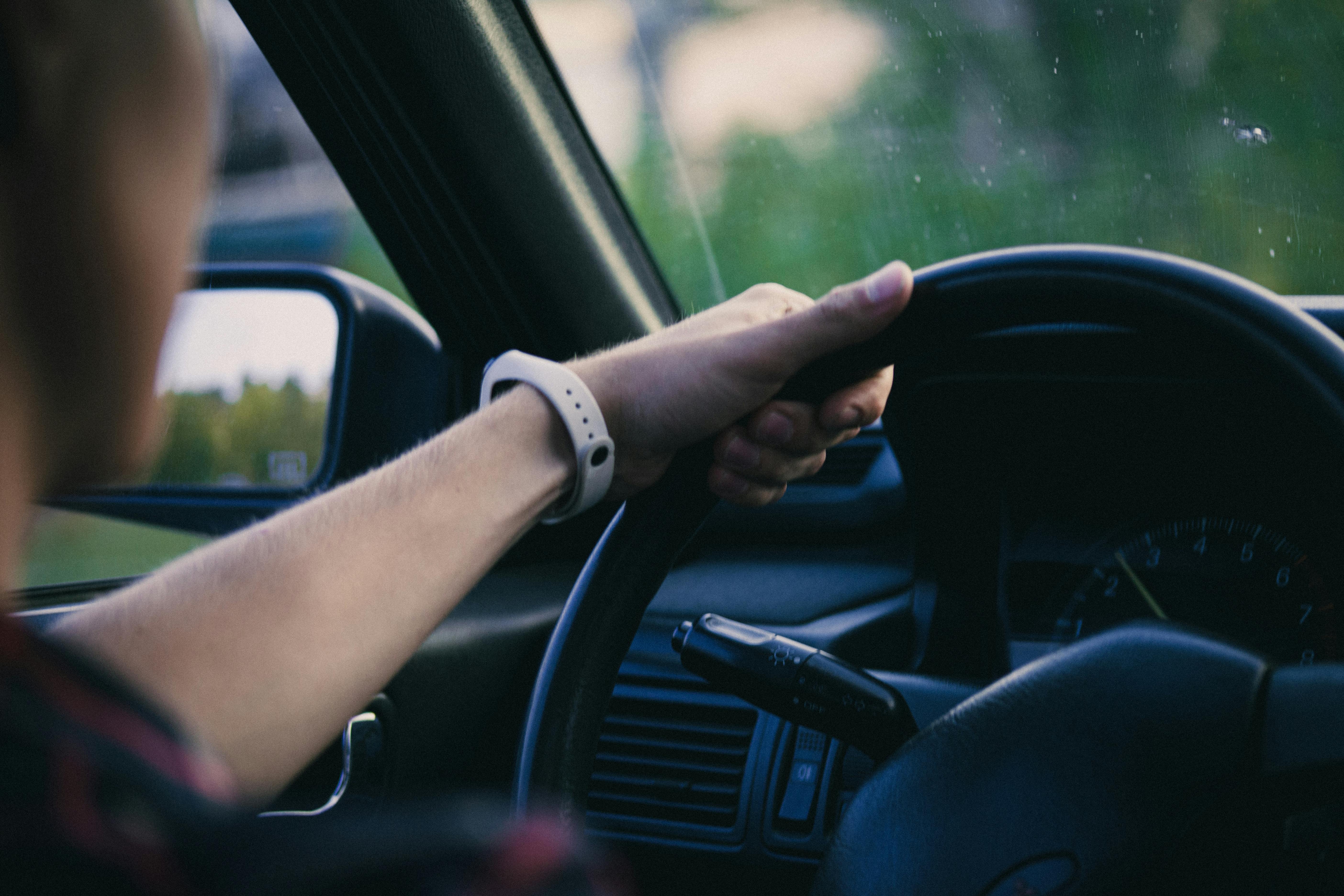 A person driving a car, hand on the steering wheel, illustrating the importance of legal vehicle handling after death.