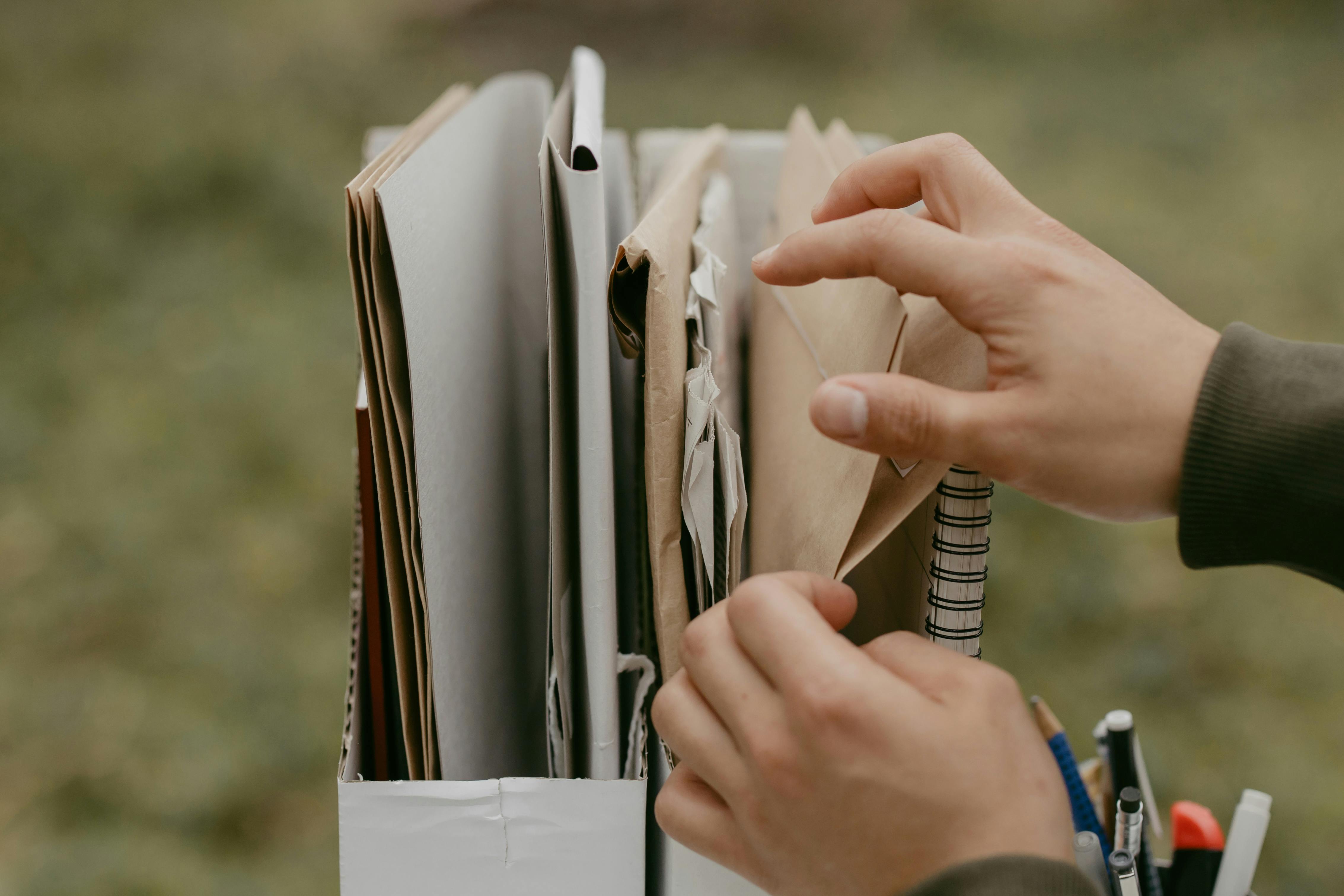A person holding a bag filled with a stack of papers, likely related to ordering certified death certificates.