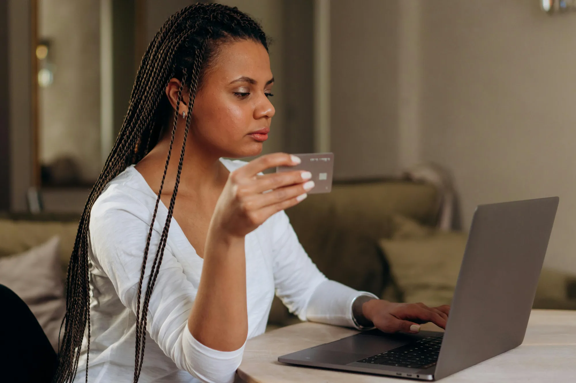A woman sits at a table with a laptop and a cup of coffee, focused on her work amidst digital subscription management.