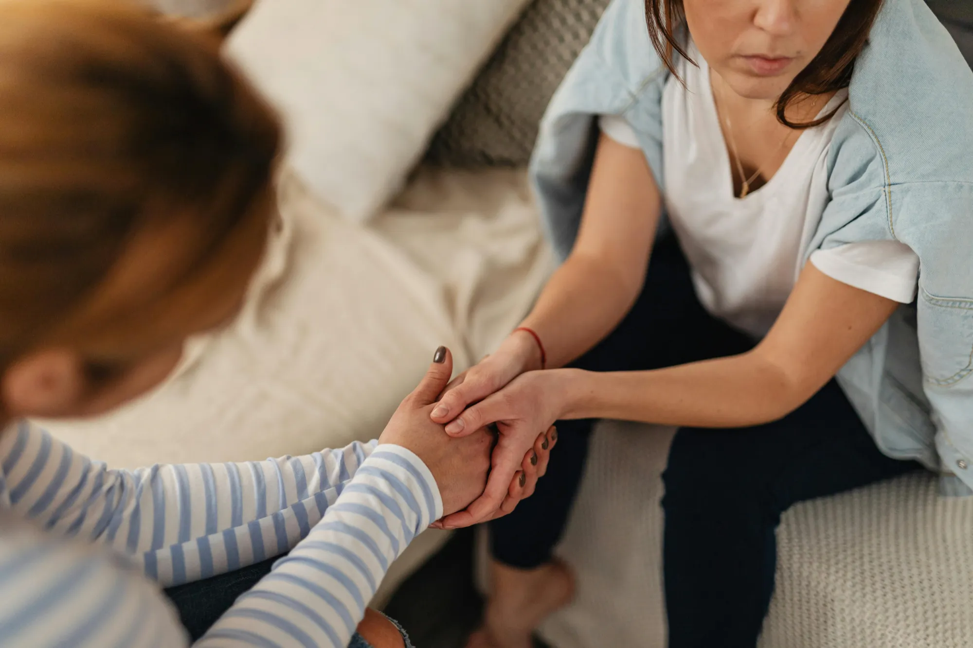 A woman holds another woman's hand, symbolizing support during challenging family estate settlements.