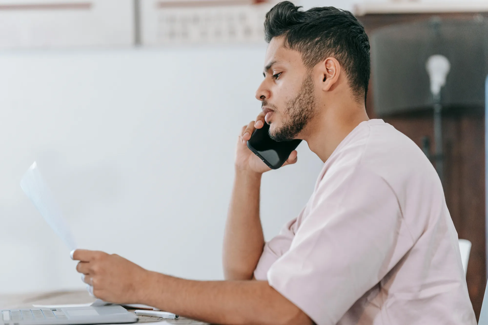 A man in a white shirt sits at a desk with a laptop and phone, focused on managing automatic payments after a loss.