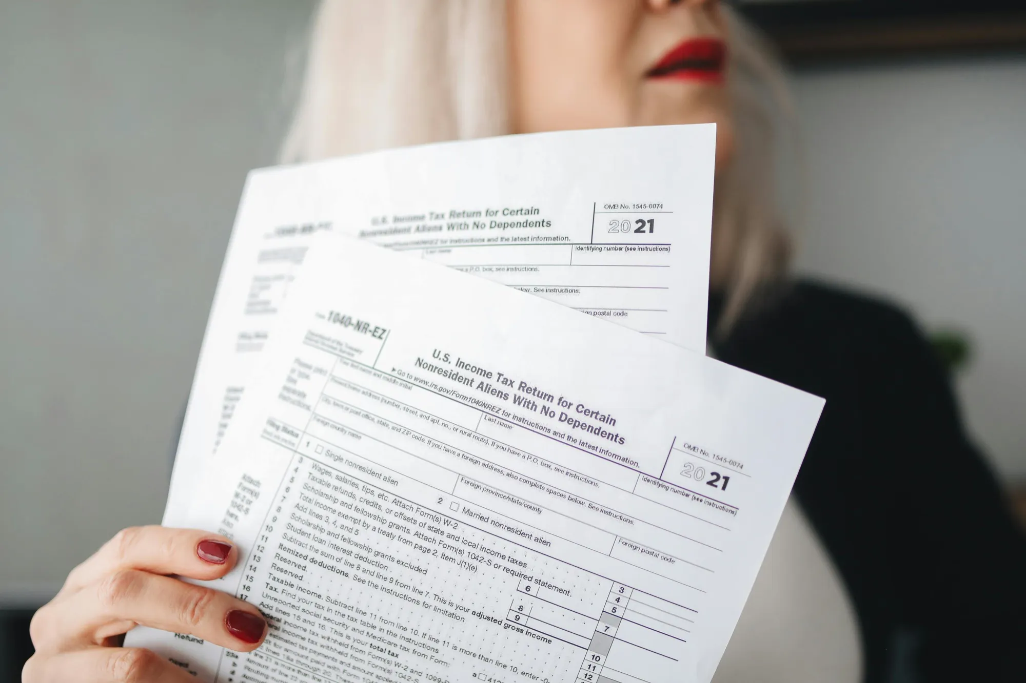A woman holding two tax forms, symbolizing the importance of managing tax records for estate protection.