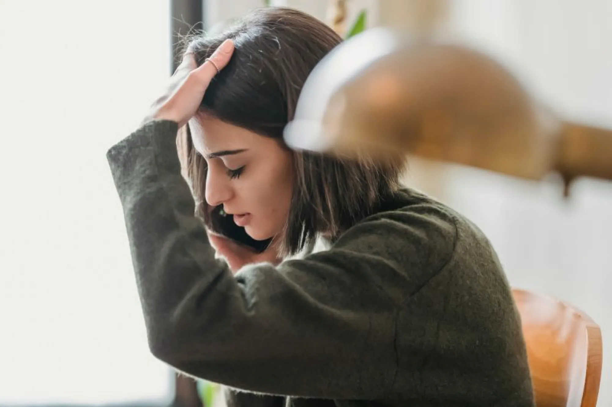 A woman sits at a desk with her head in her hands, reflecting on the immediate tasks after a death.