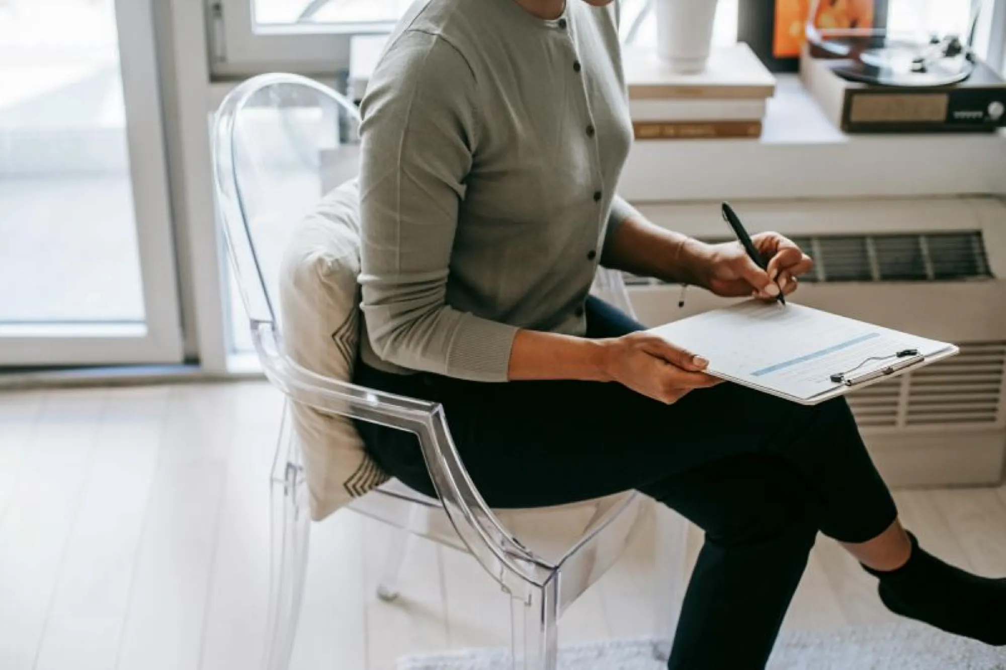 A woman sitting on a chair, writing notes on paper, with a focus on learning about Small Estate Affidavit in Illinois.