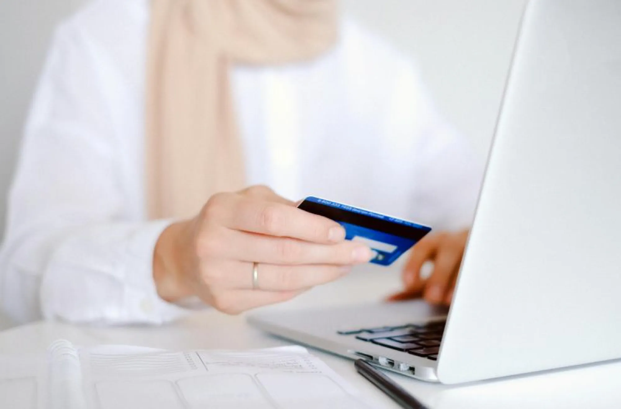 Woman using a credit card to make an online purchase, symbolizing e-commerce transactions.