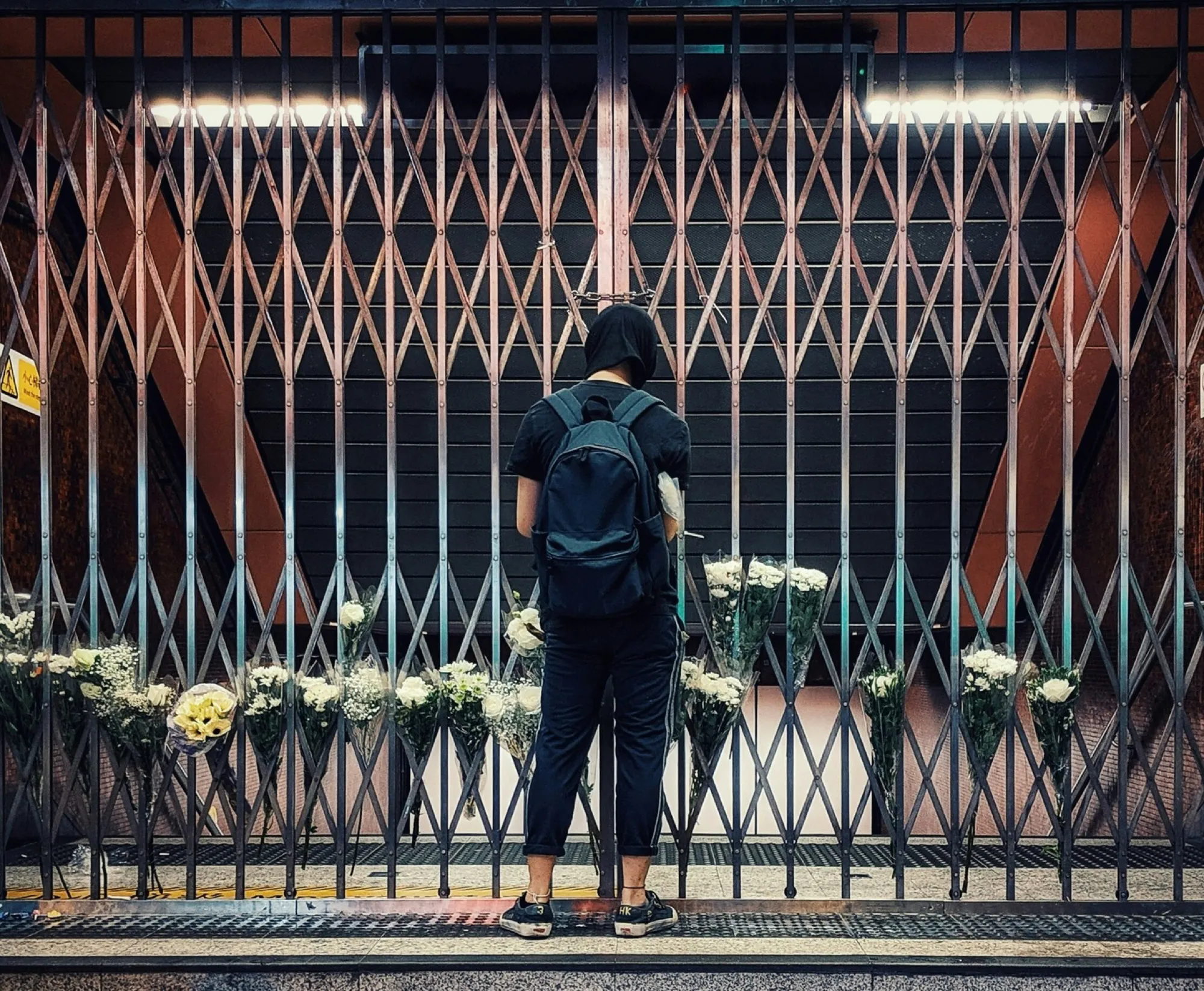 man stands by a closed train station with a bunch of flowers