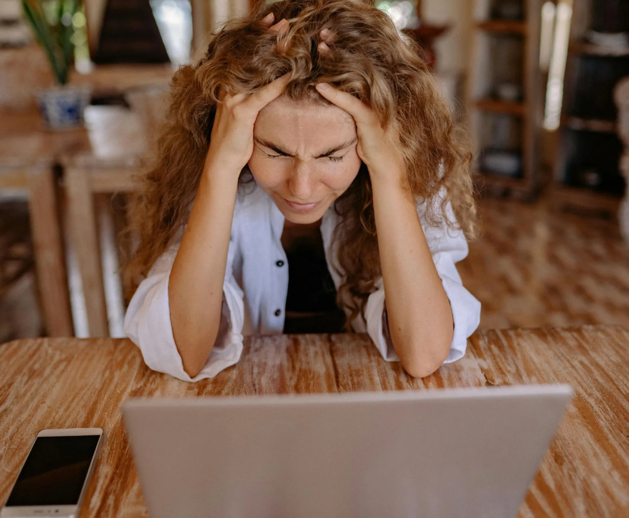 A woman sits at a table, hands on her head, contemplating strategies for balancing executor duties with her job.