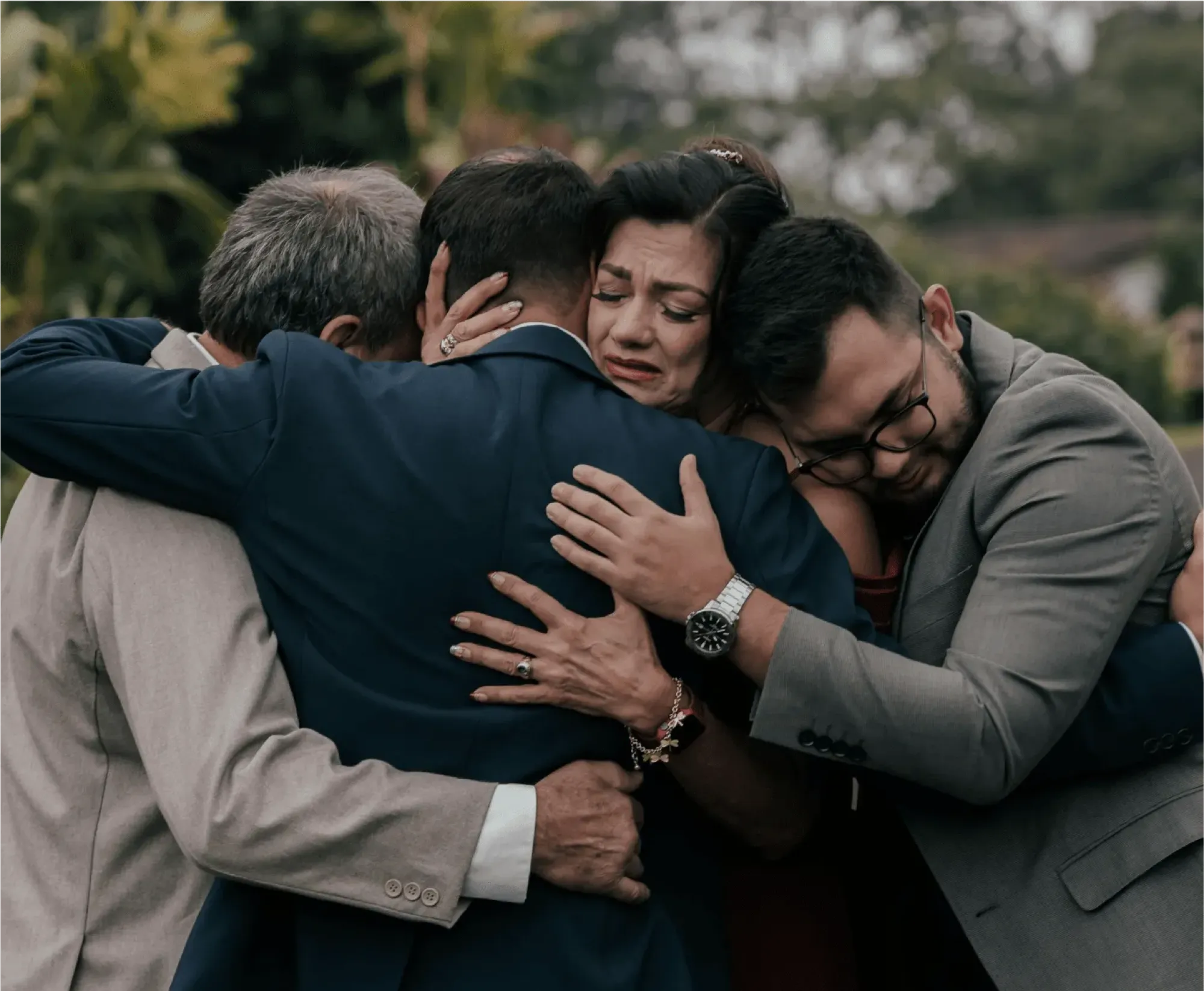 Three people embracing in a park, symbolizing support and connection during a moment of shared emotion.