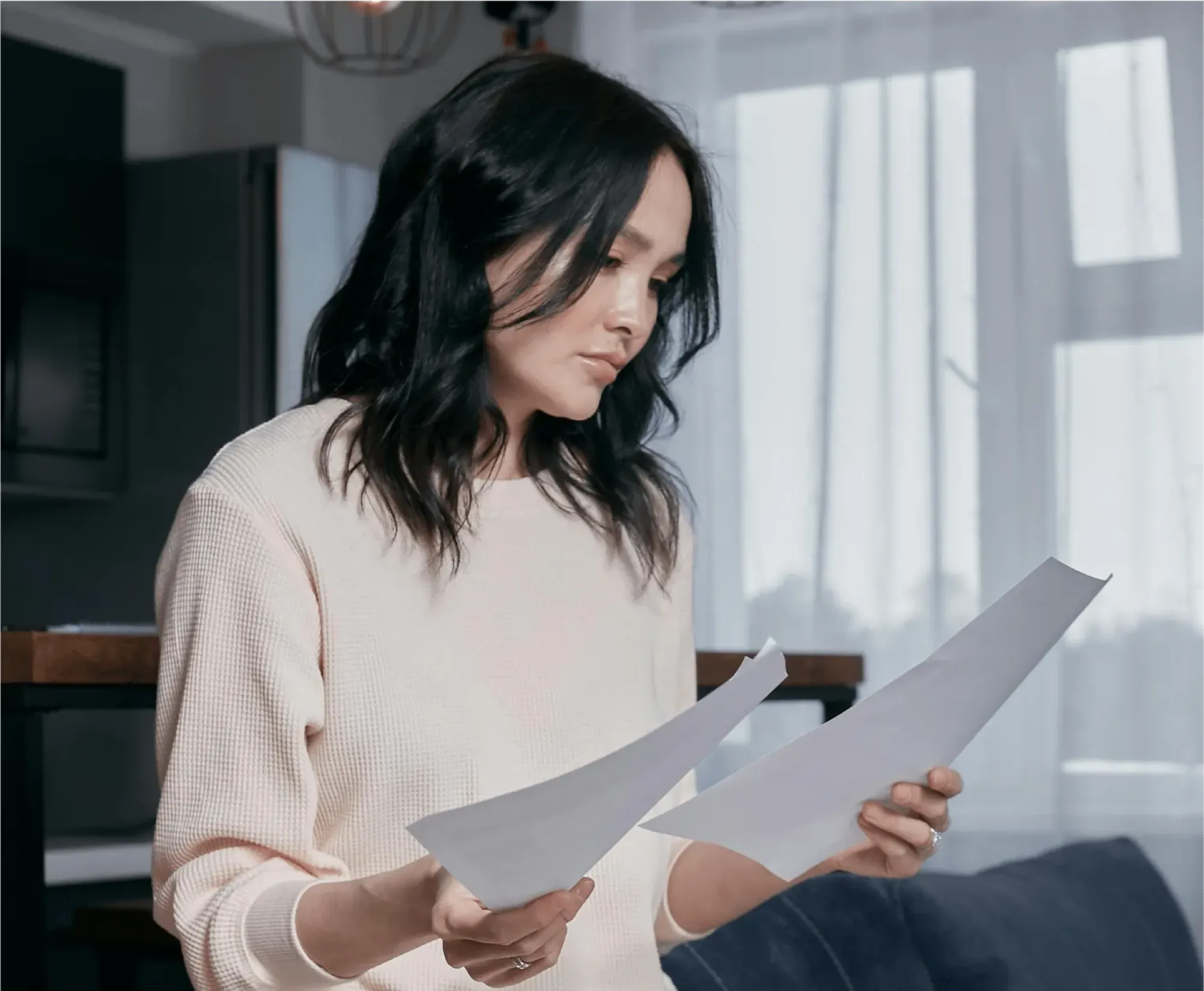 A woman sits at a desk covered with papers, contemplating executor compensation and related legal factors.