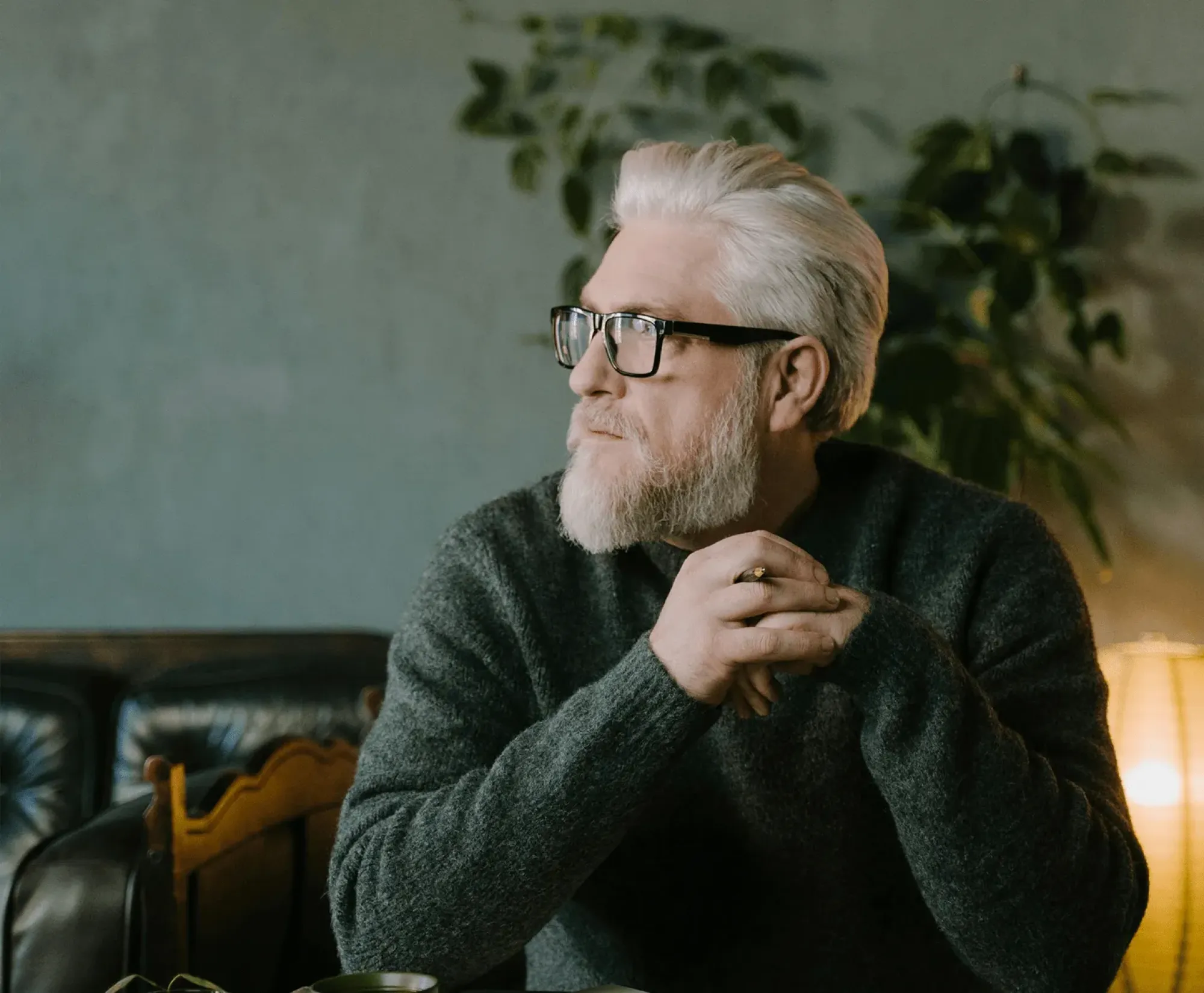 A man with glasses and a beard sitting at a table, reflecting on how to deliver a heartfelt eulogy with confidence.
