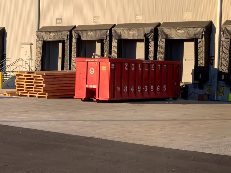 A picture of a roll-off box outside an industrial customer's loading dock.