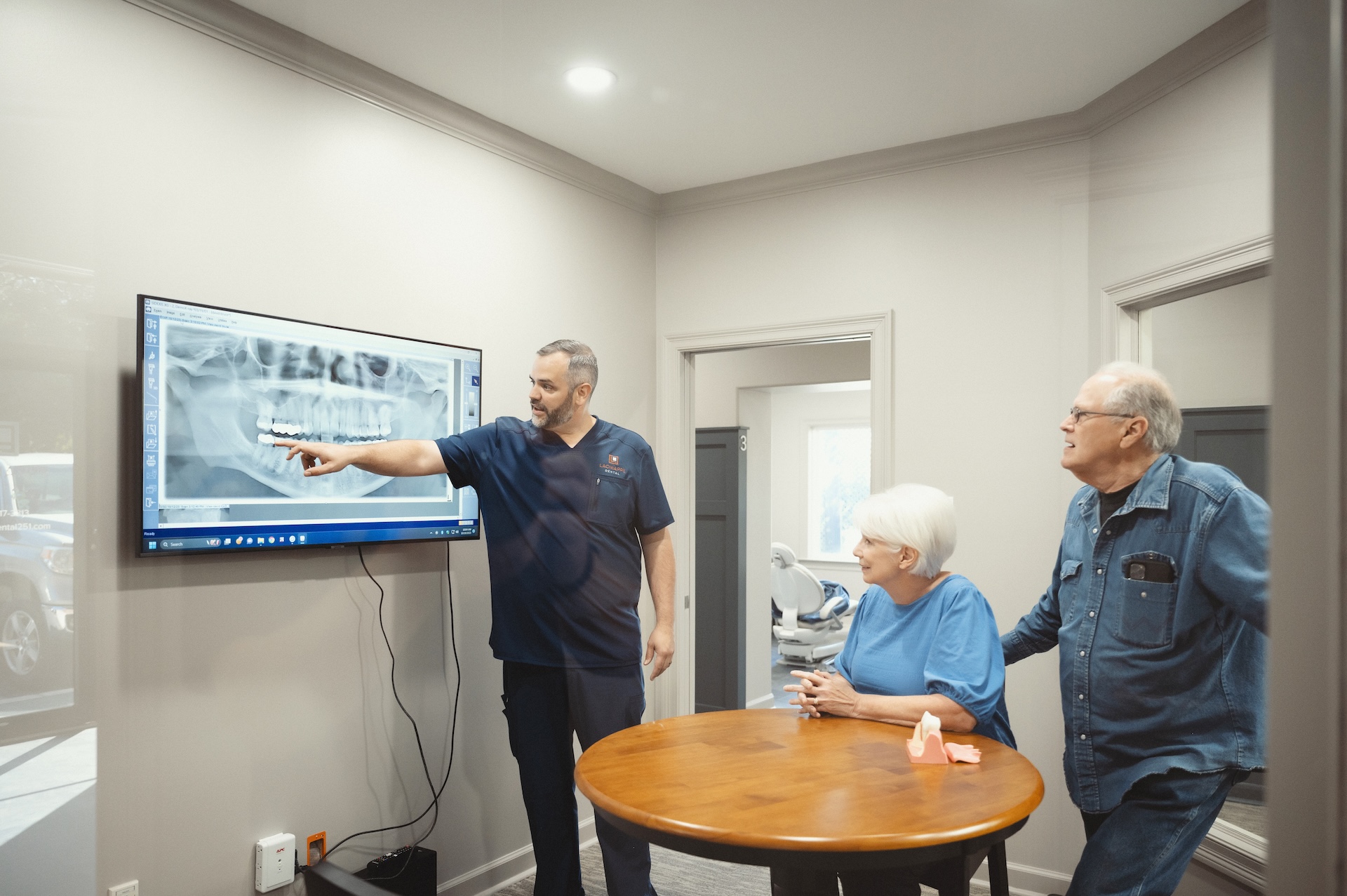 Dentist at Lagnniappe Dental showing an elderly couple an x-ray scan of a mouth