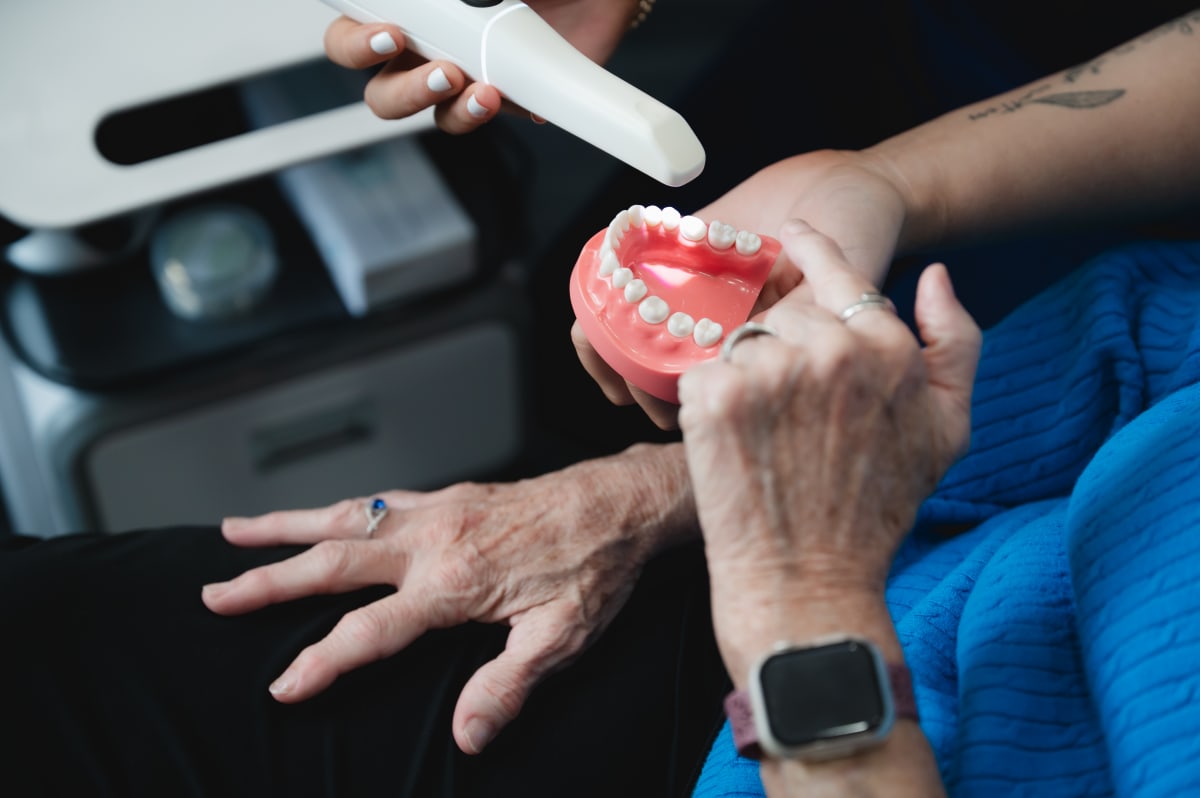 Dentist showing dental implant model to patient during consultation