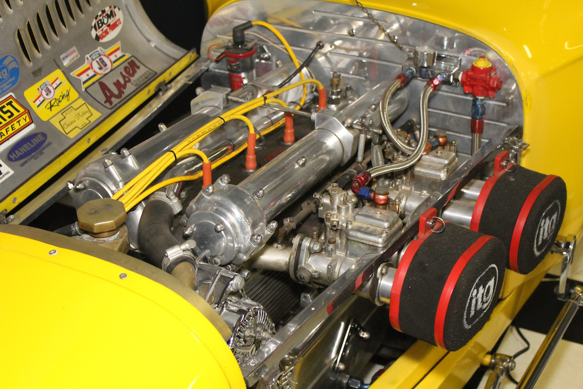 Detailed view of an Offenhauser racing engine installed in a yellow race car