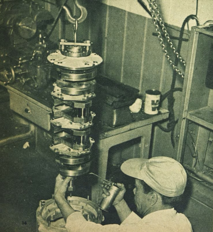 Engine builder working on a racing-engine crankshaft in a workshop