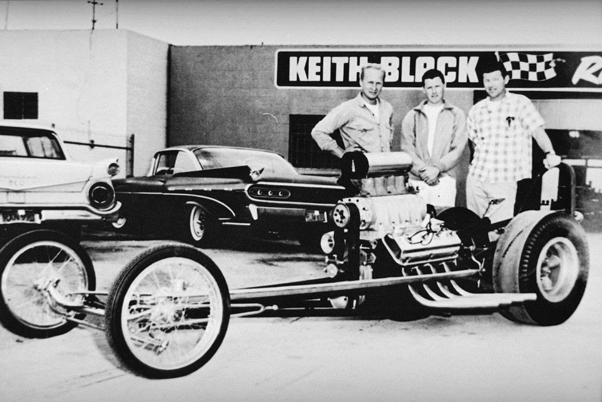 Keith Black and colleagues standing behind a dragster outside the Keith Black racing shop