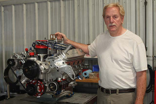 Robert Yates standing beside a completed racing engine in a workshop