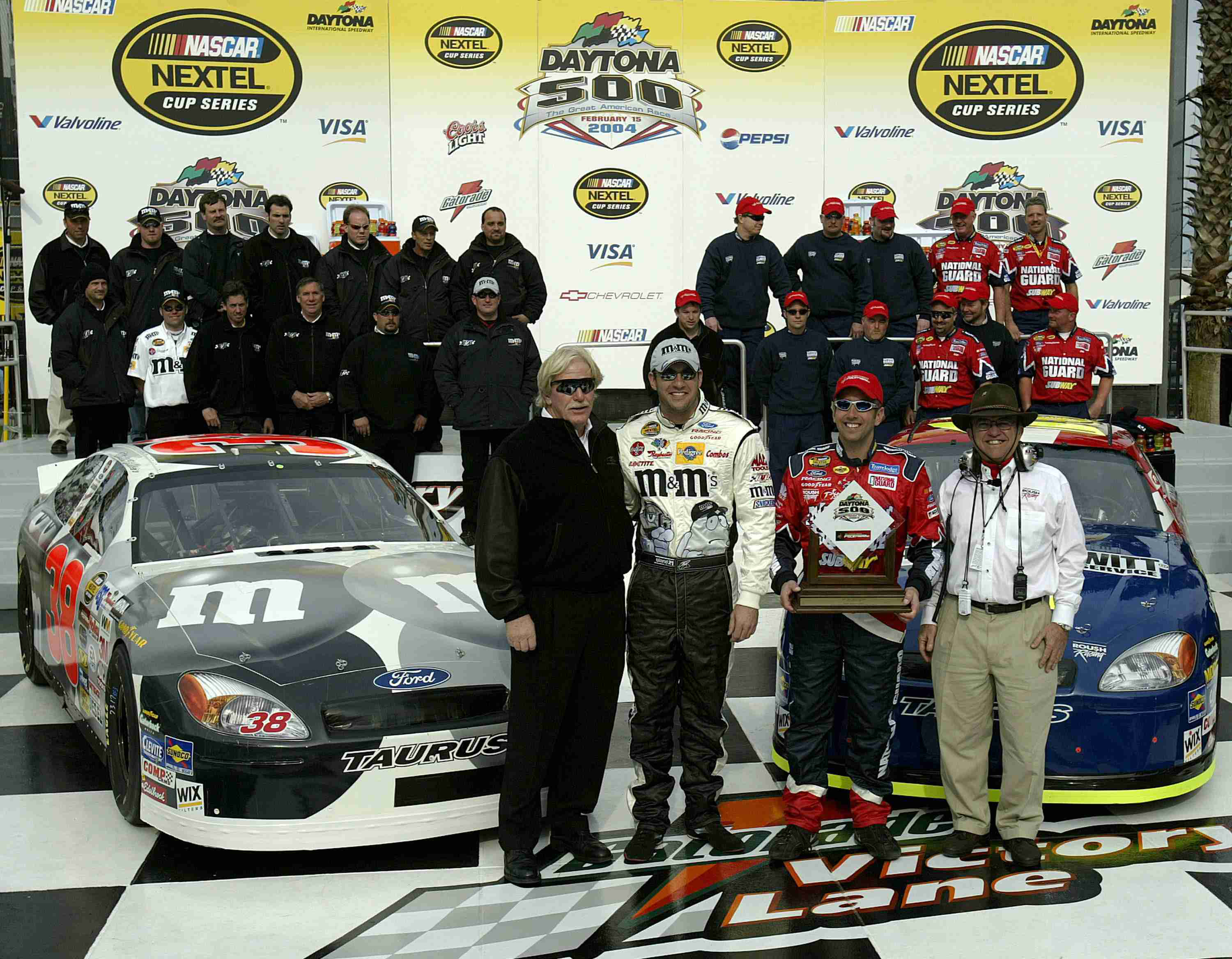 Robert Yates and team members with two Ford race cars during Daytona Speedweeks in 2004
