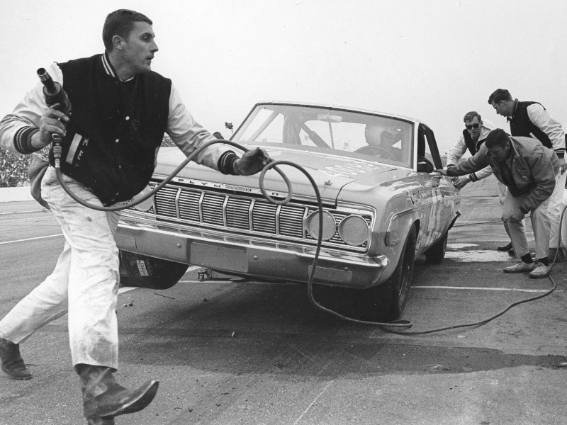 Maurice Petty carrying an air hose as the Petty crew services a Plymouth race car