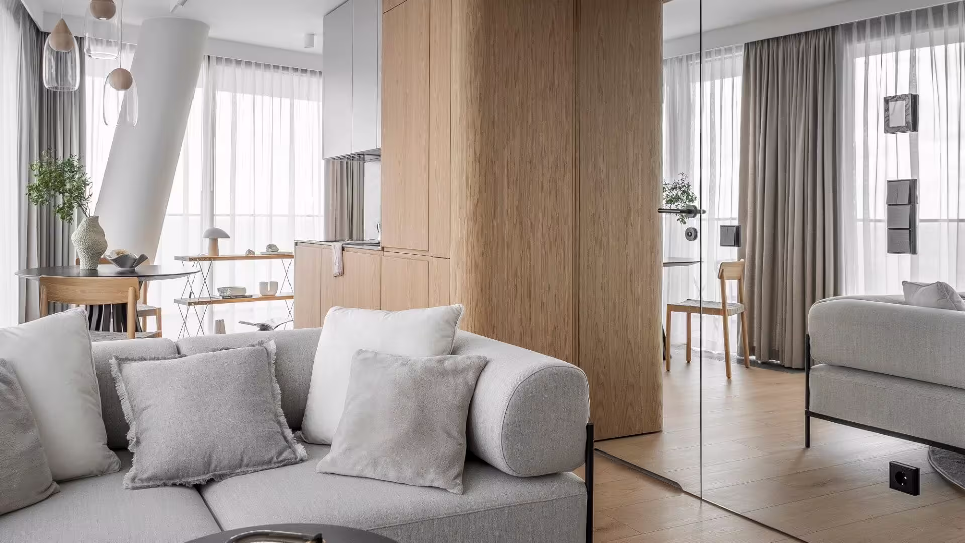 Nowoczesny salon z firanami i szarymi zasłonami, drewnianą zabudową i lustrem – realizacja dekoracji okiennych na wymiar Hanna Szlachetko we współpracy z Mindful Architekci