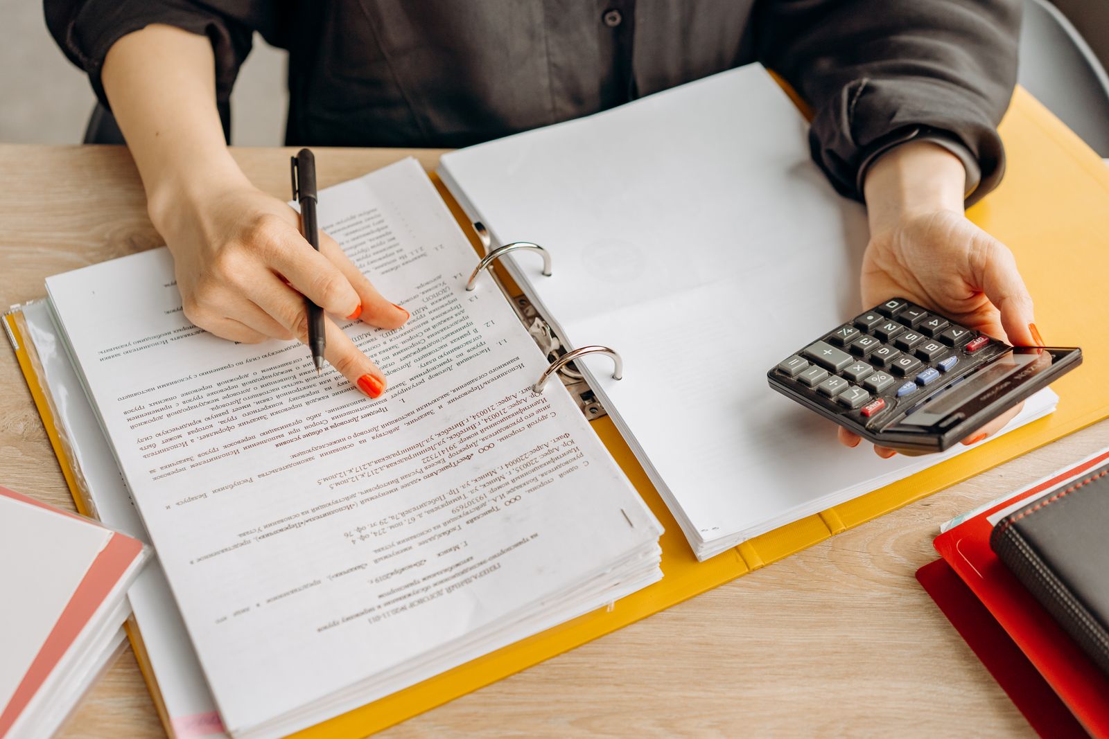 Person reviewing documents in a binder with a calculator