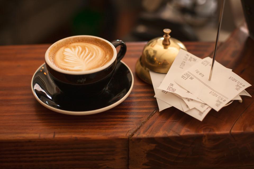 Cup of coffee next to a service bell and paper receipts