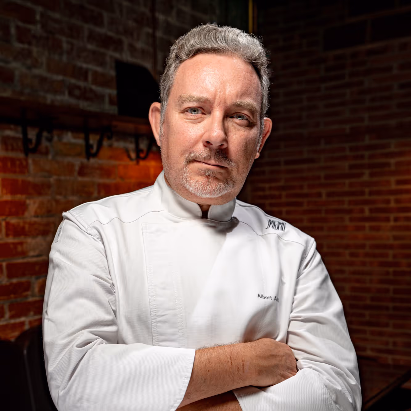 Albert Adria en gilet de chef blanc aux bras croisés.