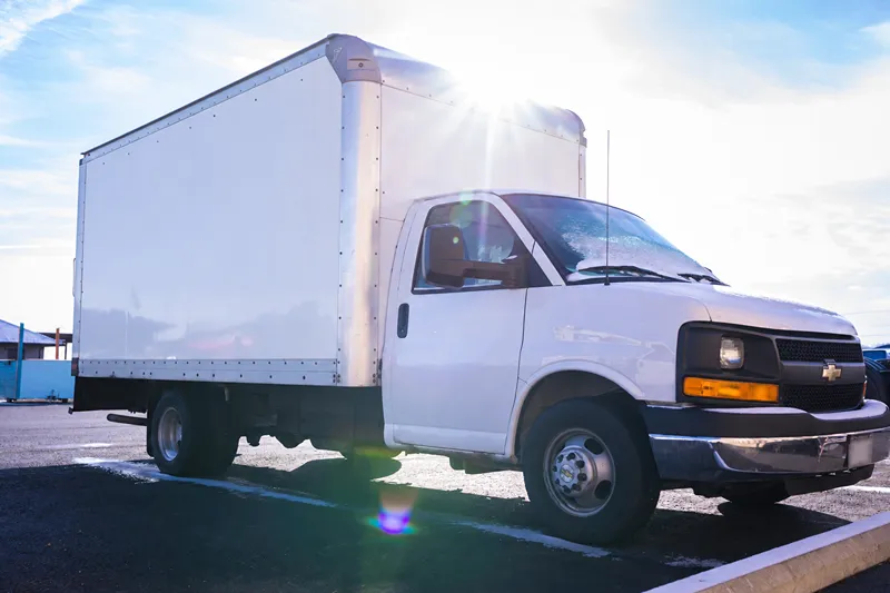 White Chevrolet box truck parked outdoors in bright sunlight, ready for heavy-duty truck maintenance and repair.