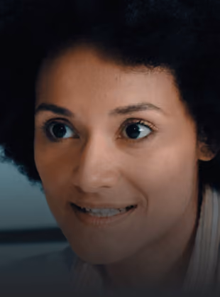 Close-up of woman with curly hair smiling slightly and looking to her left.
