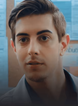 Close-up of a young man with short brown hair, looking directly at the camera.