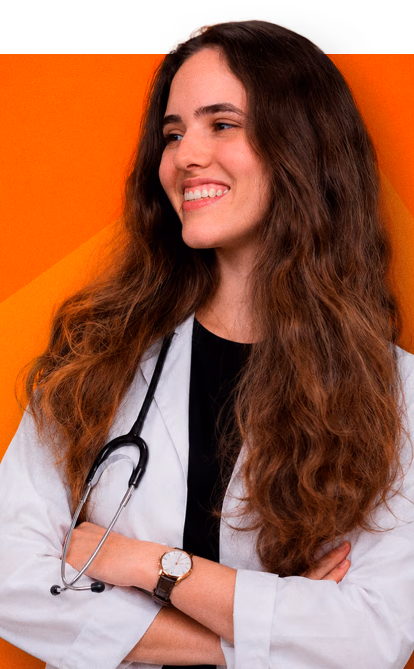 Smiling female doctor with long hair wearing a white coat and stethoscope against orange background.