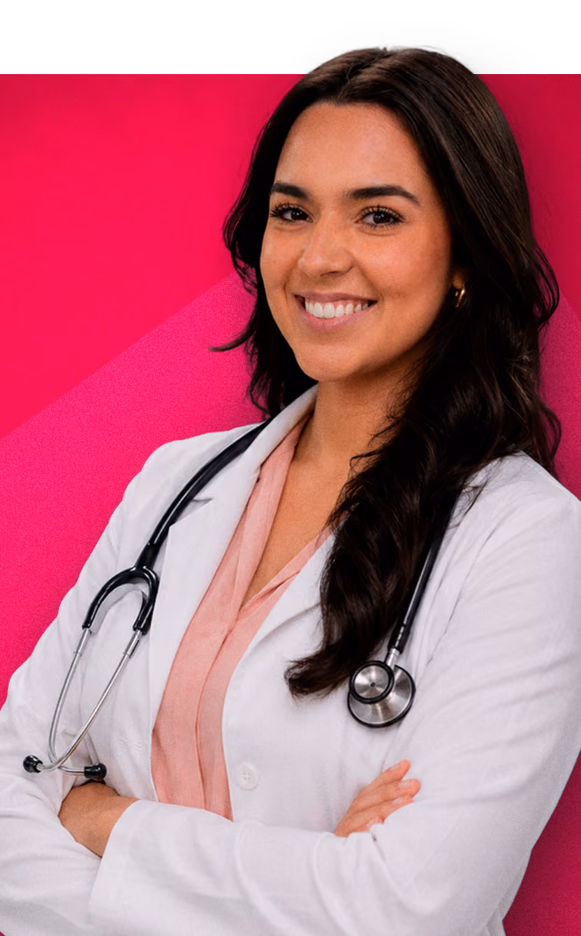 Smiling female doctor in a white coat with a stethoscope against a pink background.