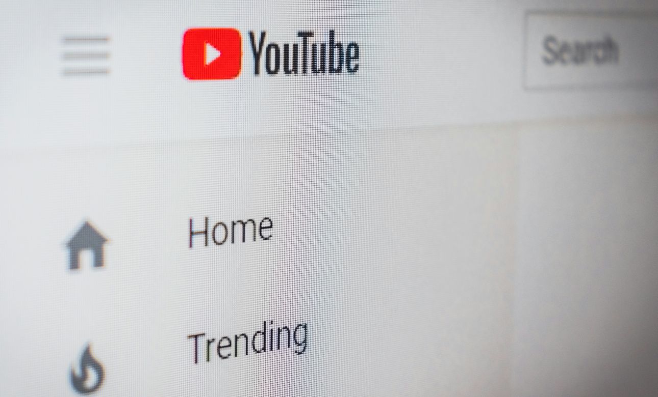 Close-up of the YouTube homepage navigation on a screen, showing the YouTube logo alongside the Home and Trending menu links.