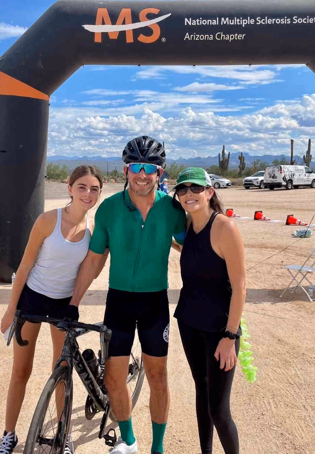 A photo of Andrew Rafal and his family, Jules Rafal, and Winter Rafal standing at the finish line of the Bike MS Arizona supporting the charity and riding for a cause on behalf of Bayntree Wealth Advisors Scottsdale