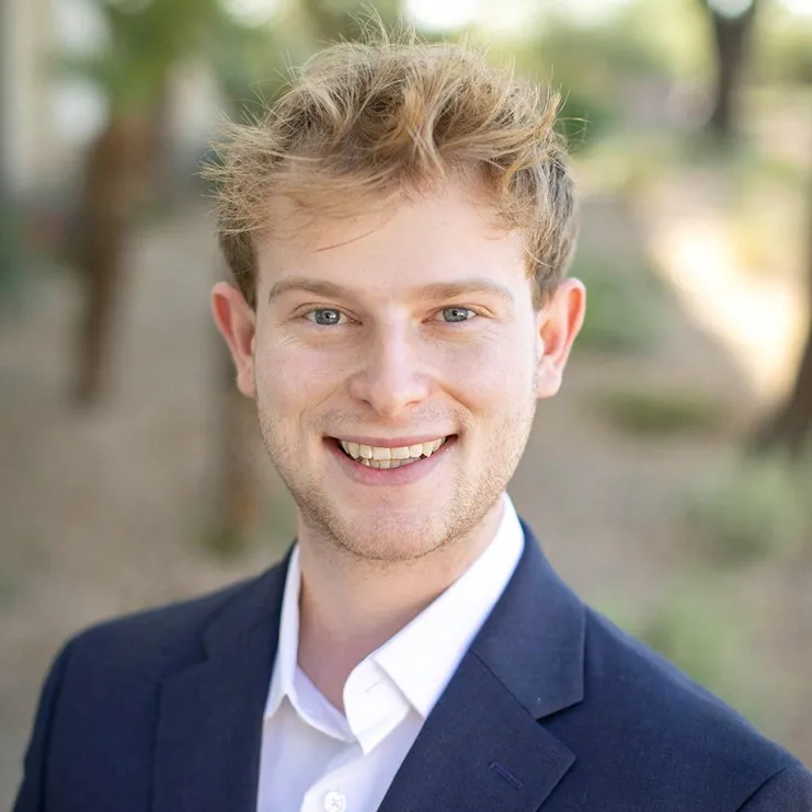 A man in a suit smiling at the camera.