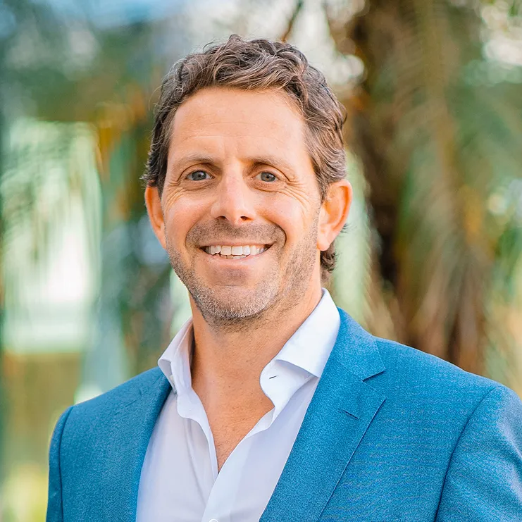 A man in a blue suit smiling at the camera.