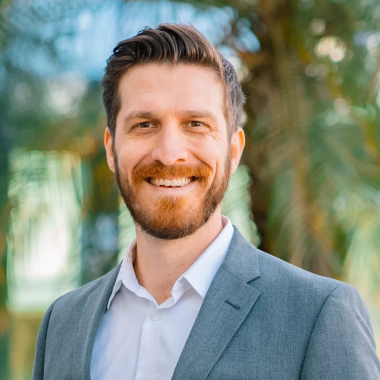A man with a beard wearing a suit and smiling.