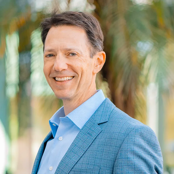 A man in a blue suit smiling at the camera.