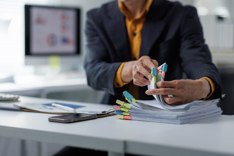 Professional hands preparing stacks of reports and financial papers at an office desk, managing important administration tasks