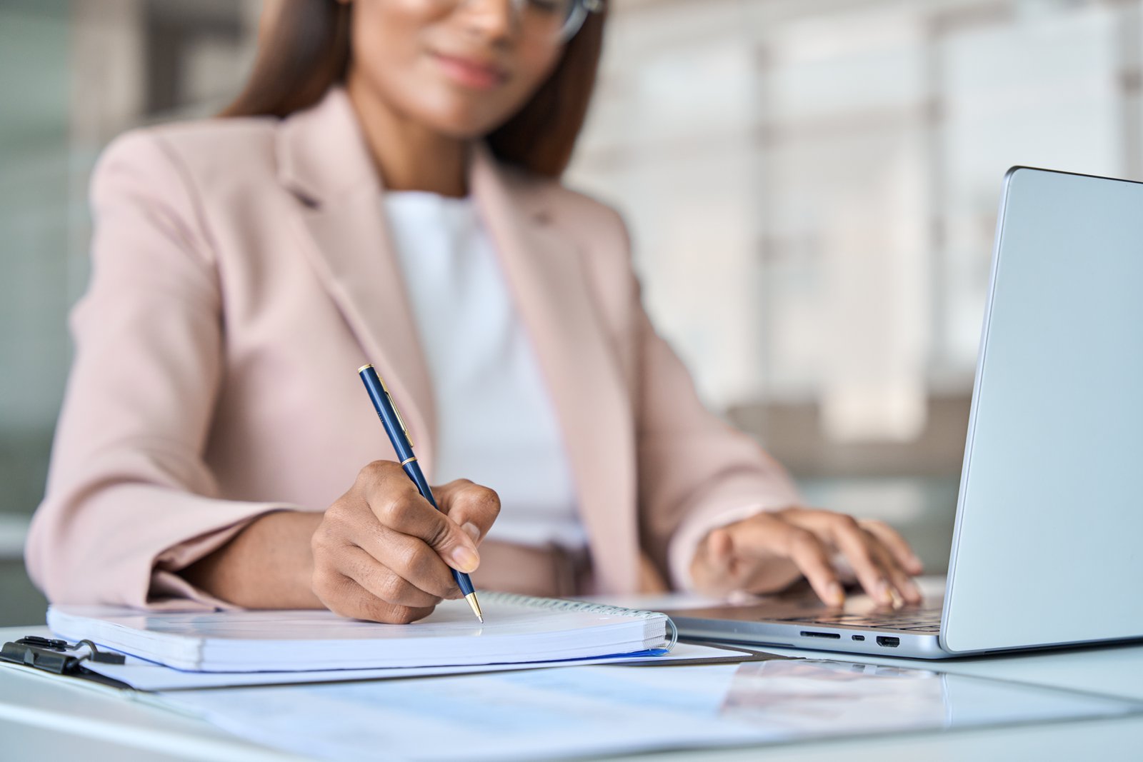 Woman reviewing employment documents and taking notes at her desk