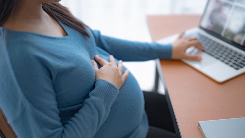 Pregnant employee researching California pregnancy leave rights on her laptop