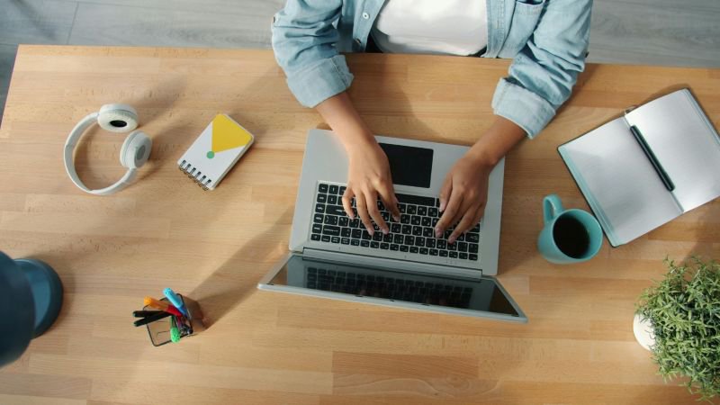 Employee documenting evidence of workplace retaliation by writing notes and typing on laptop
