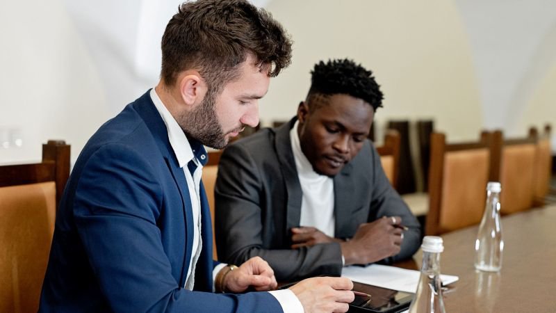 Two men in business attire review documents on a tablet together at a conference table, representing an employee consulting with legal counsel about California employment claim deadlines.