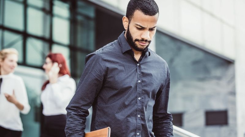 Employee leaving office building after being laid off and waiting on a late final paycheck in California