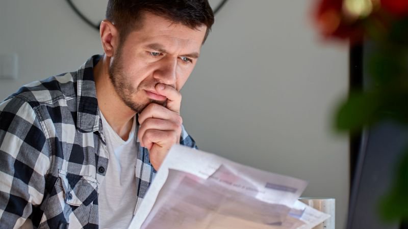 Employee reviewing pay stubs and documents at home to calculate California waiting time penalties owed